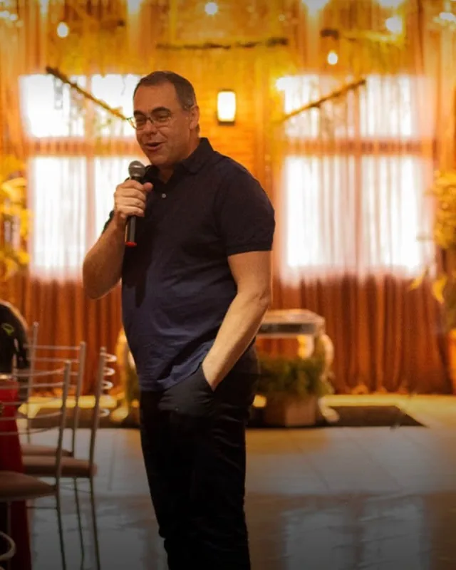 Miguel Rossato de microfone na mão, falando em um evento